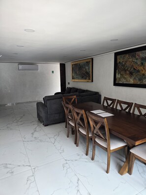 A spacious room with a marble floor, a wooden dining table with chairs, a grey sofa, and two abstract paintings on the walls. - 🛥Marina Vallarta 3BR | Yacht Harbor | Pool & Near the Beach (Puerto Vallarta)