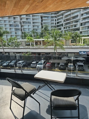 A balcony with two chairs and a table, overlooking a parking area and a modern building with balconies. - 🛥Marina Vallarta 3BR | Yacht Harbor | Pool & Near the Beach (Puerto Vallarta)