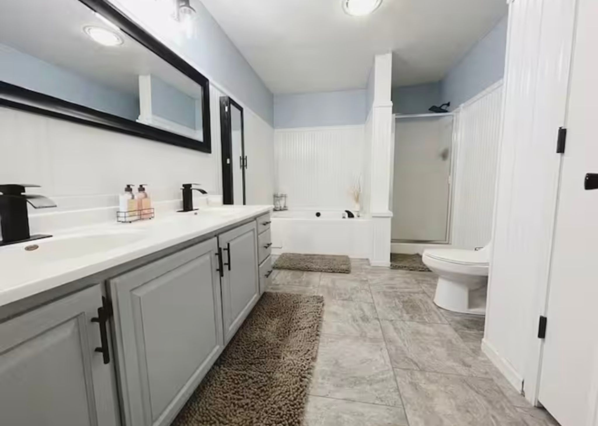 Ein modernes Badezimmer mit einem großen Spiegel, einer Badewanne und einer Toilette.