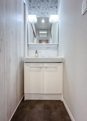 Ein Badezimmer mit weißem Waschtisch, einem Spiegel und einer Wandleuchte.