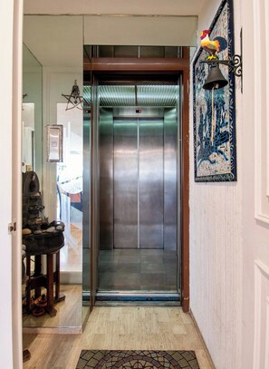 An elevator with a digital display, a decorative rooster, and a mosaic wall. - Polanco Connected | South, North & Mexico City (Mexico City)