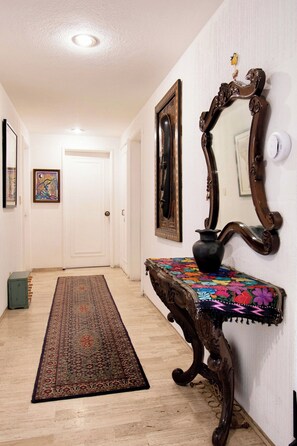 A hallway with a patterned rug, a wooden console table with a vase, and a mirror on the wall. - Polanco Connected | South, North & Mexico City (Mexico City)