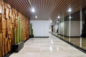 A corridor with a wooden wall on one side and a glass wall on the other, leading to a room with a white ceiling and recessed lighting. - Polanco Connected | South, North & Mexico City (Mexico City)
