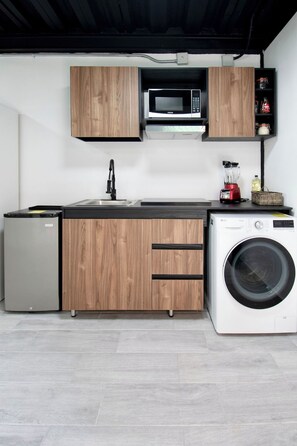 A compact kitchen with wooden cabinets, a microwave, a sink, a refrigerator, and a washing machine. - Modern Loft · 10 Min from Coyoacán Center (Mexico City)