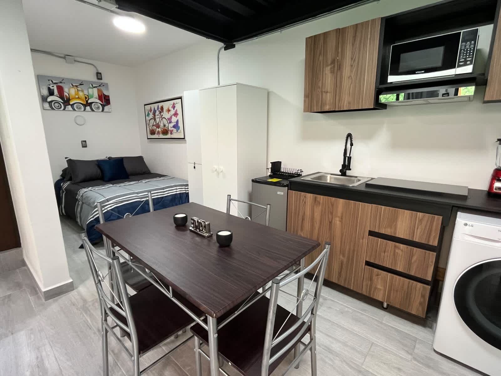 Una cocina compacta equipada con microondas, lavamanos y lavadora.