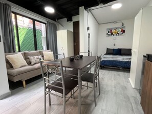 A modern living space with a sofa, dining table, chairs, a bed, and artwork on the wall. - Modern Loft · 10 Min from Coyoacán Center (Mexico City)