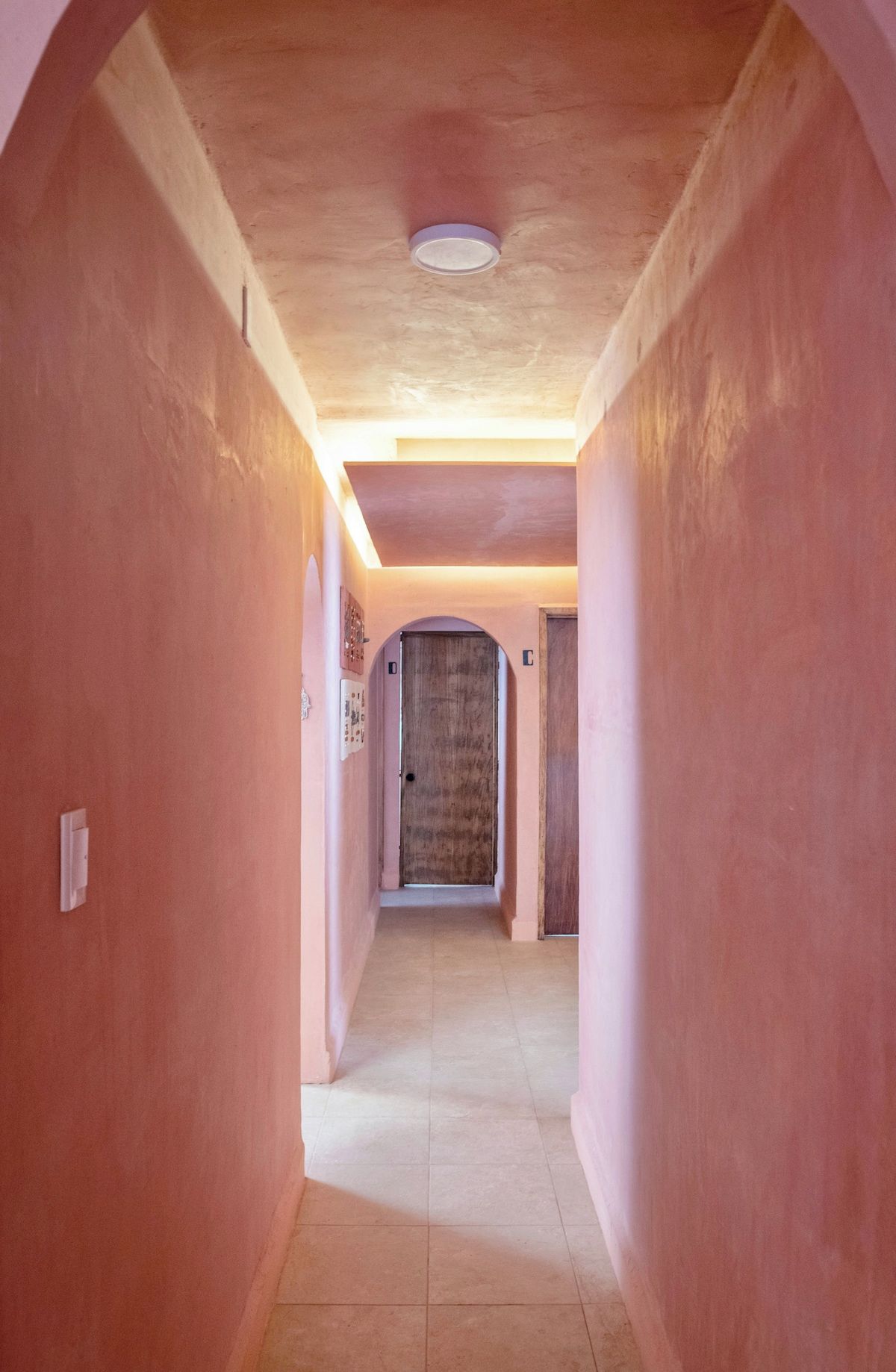 A corridor with a tiled floor and a door at the end.