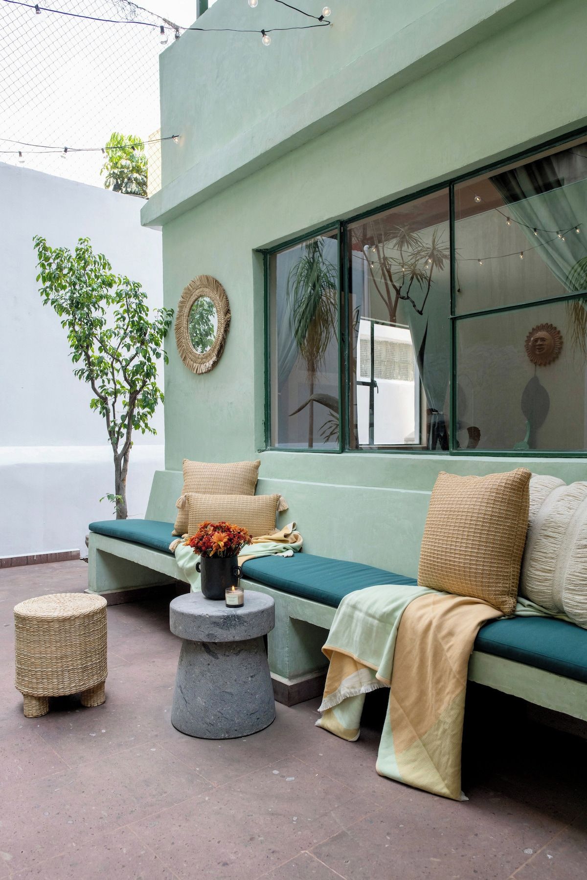 A seating area with a bench and a table, a potted plant, and a wall-mounted mirror.