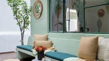 A seating area with a bench and a table, a potted plant, and a wall-mounted mirror.