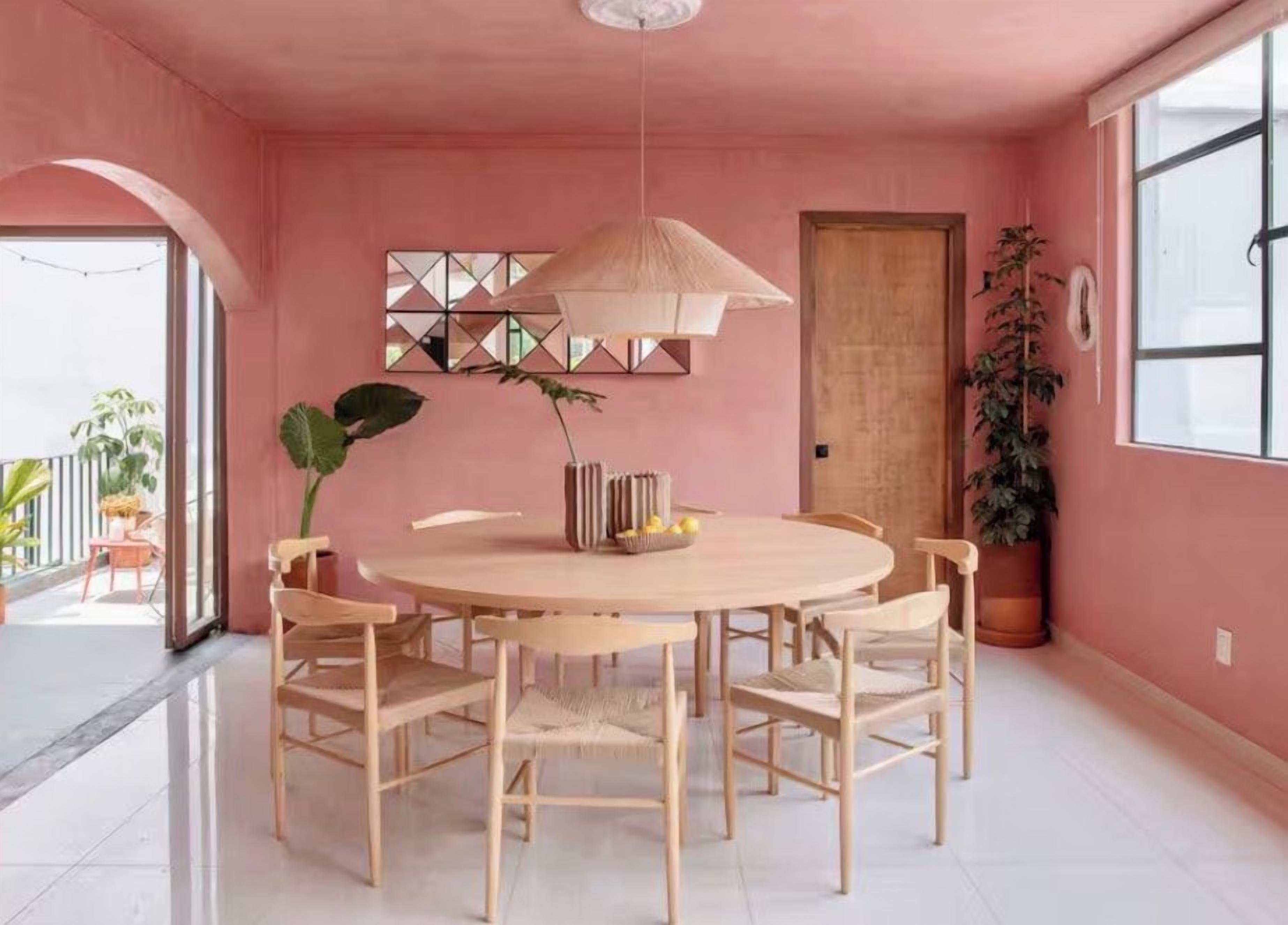 A dining area with a round table and chairs, a hanging light fixture, and a potted plant.