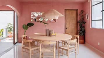 A dining area with a round table and chairs, a hanging light fixture, and a potted plant.