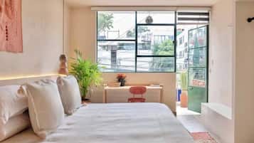 A bedroom with a bed, a desk, and a window overlooking a street.