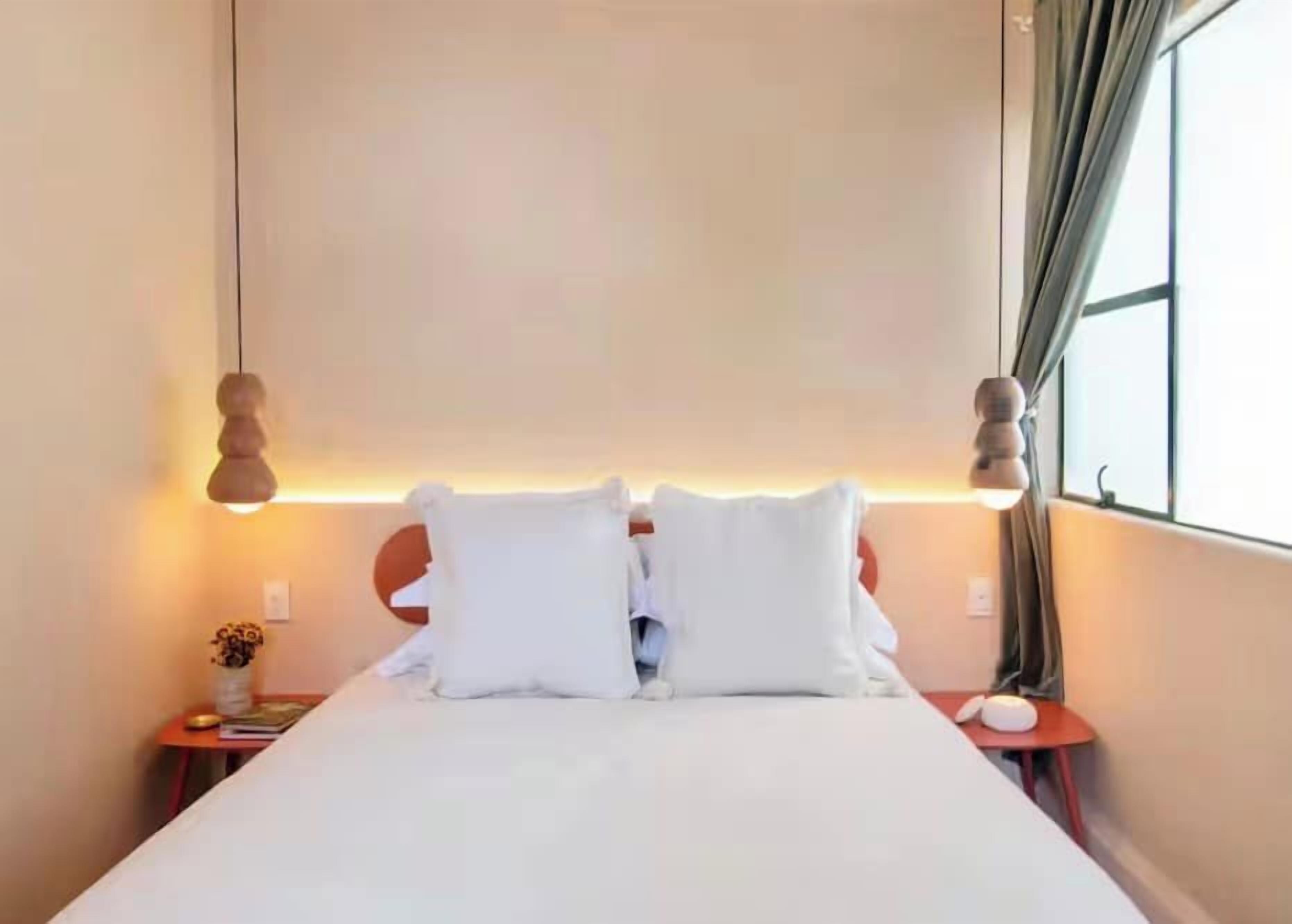 A hotel room with a bed, bedside tables, a lamp, and a window with curtains.