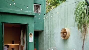 A cozy outdoor seating area with wicker furniture, a potted plant, and a string of lights.