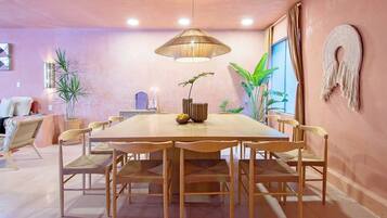 A dining area with a round table, wooden chairs, and a hanging light fixture.