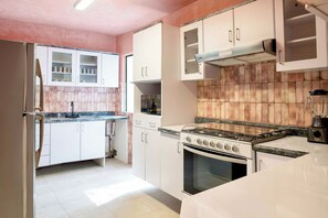 Cozinha com armários brancos, fogão e painel de azulejos.