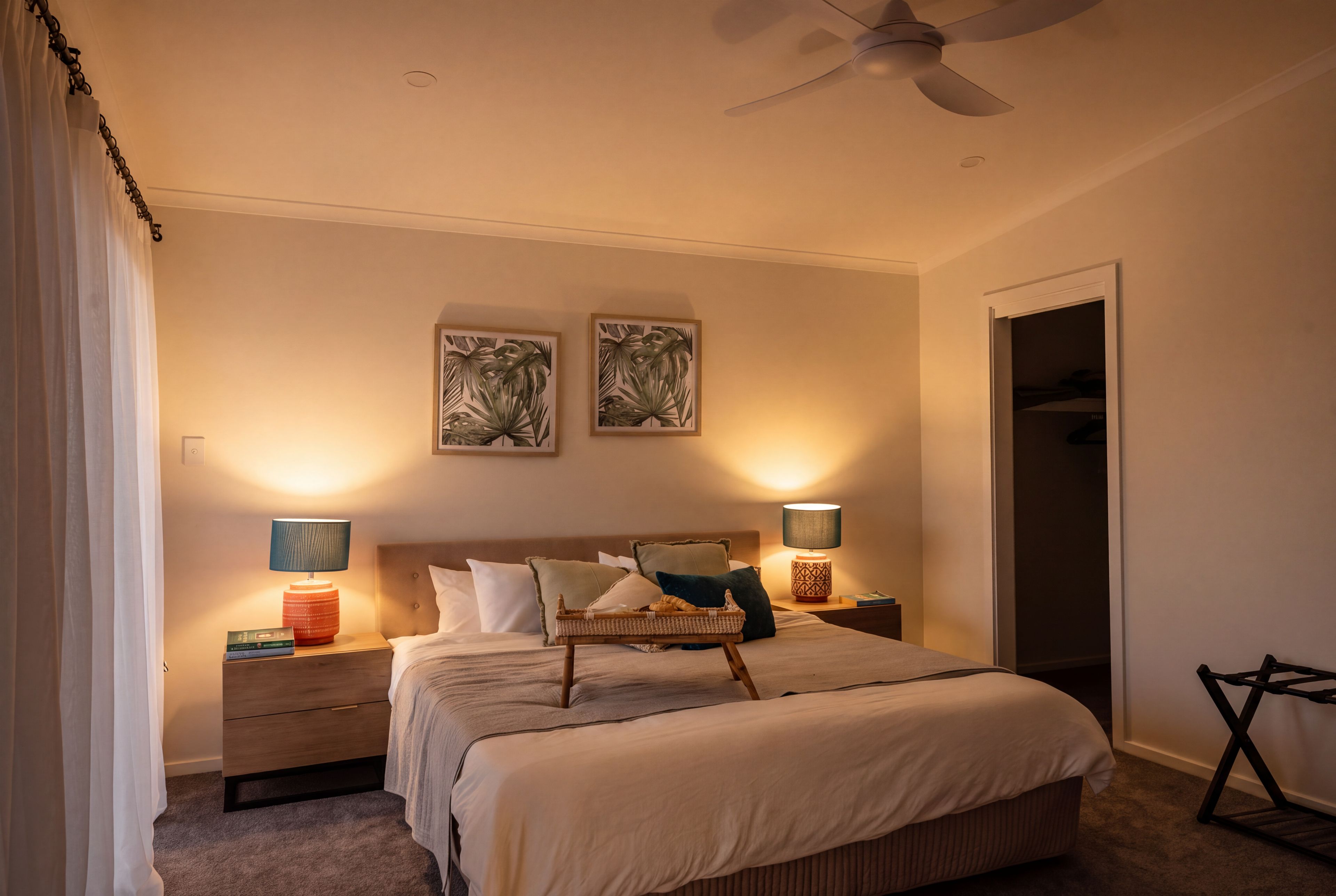A bedroom with a bed, two bedside tables, a ceiling fan, and two wall-mounted lamps.