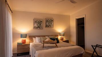 A bedroom with a bed, two bedside tables, a ceiling fan, and two wall-mounted lamps.