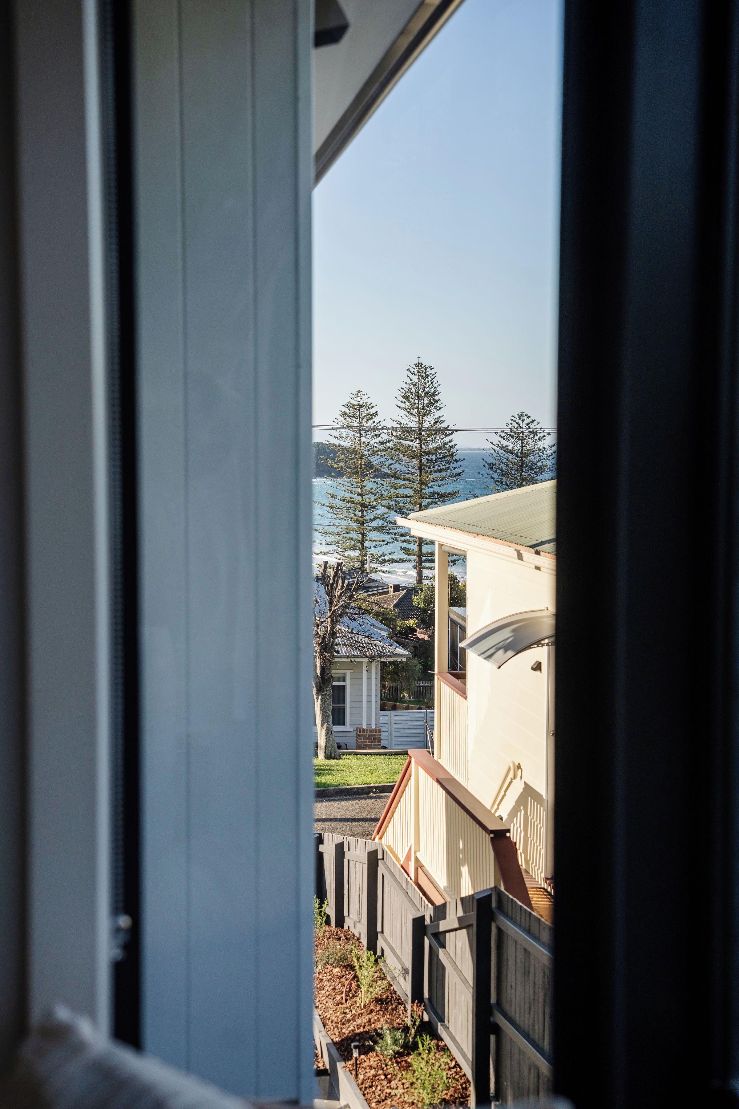 Une vue à travers une fenêtre donnant sur un quartier résidentiel, avec des maisons et un plan d’eau.