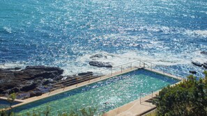 Una piscina con vista al océano y a la costa rocosa.