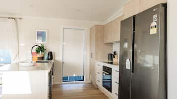 A modern kitchen with a stainless steel refrigerator, wooden cabinets, and a built-in oven.