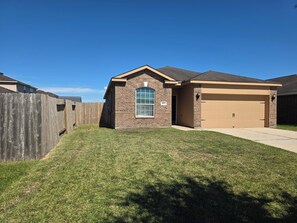 A residential house with a garage, a brick exterior, and a well-maintained lawn. - Charming 3-bedroom house with AC in Rosharon (Rosharon)