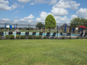 A fenced pool area with lounge chairs and a tree. - Charming 3-bedroom house with AC in Rosharon (Rosharon)