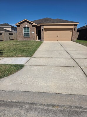 A residential house with a garage, a well-maintained lawn, and a clear sky. - Charming 3-bedroom house with AC in Rosharon (Rosharon)