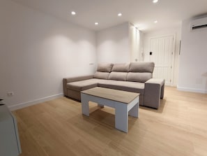 Een moderne woonkamer met een modulaire bank, een salontafel en inbouwspots.