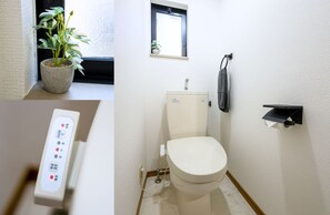 Un baño con inodoro, una ventana pequeña, una planta en maceta y un panel de control.