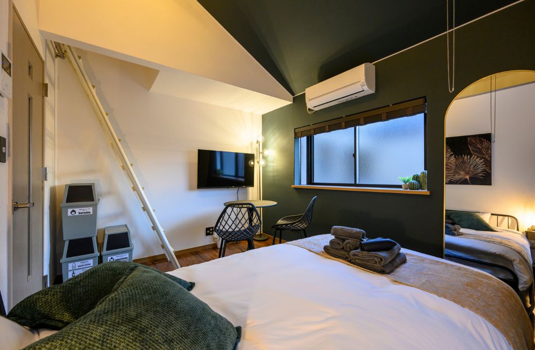 Un dormitorio con cama, escritorio, silla, televisor y ventana.