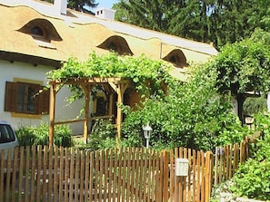 A house with a wooden fence, a pergola with climbing plants, and a street lamp. - Cottage in Szigliget With Swimming Pool (Szigliget)