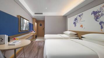 Una habitación de hotel con cama, escritorio con silla, televisión y un mapa mundial en la pared.