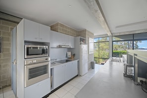 Eine moderne Küche mit eingebauten Geräten, einem großen Fenster und Blick auf Grünflächen.