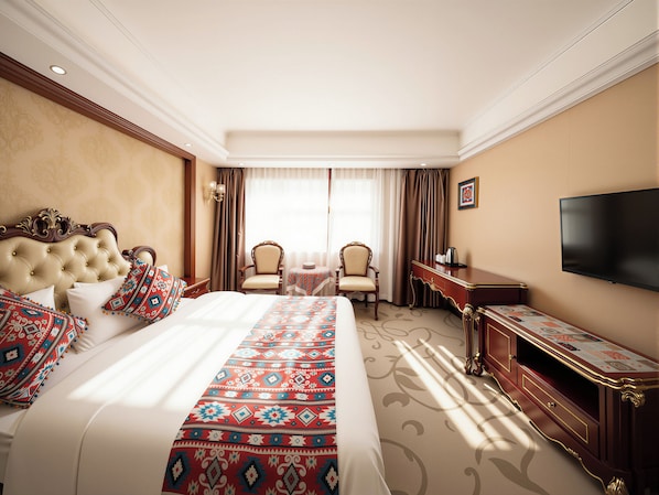 A hotel room with a large bed, two chairs, a small table, a TV, and a desk.