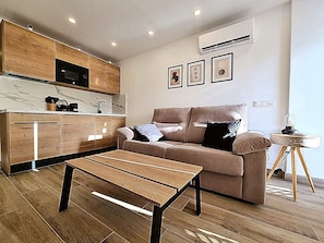 A modern living space with a kitchen, a sofa, a coffee table, and a small side table. - A SMALL APARTMENT IN MASPALOMAS (Maspalomas)