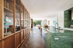 A modern kitchen with wooden cabinets, a marble countertop, and a view of the garden. - Vogue House, Dover Heights (Dover Heights)