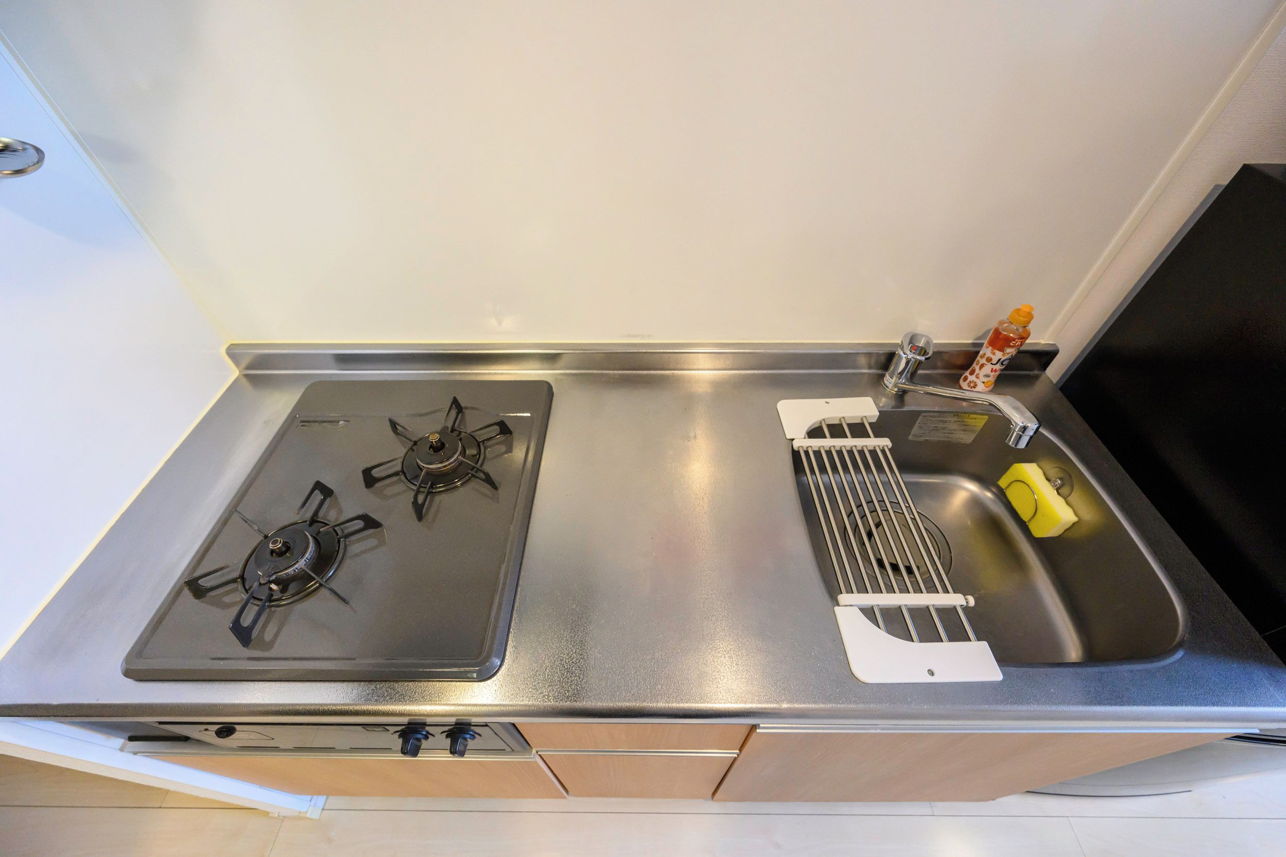 A kitchen with a gas stove, a sink, and a small bottle of dish soap.