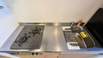 A kitchen with a gas stove, a sink, and a small bottle of dish soap.