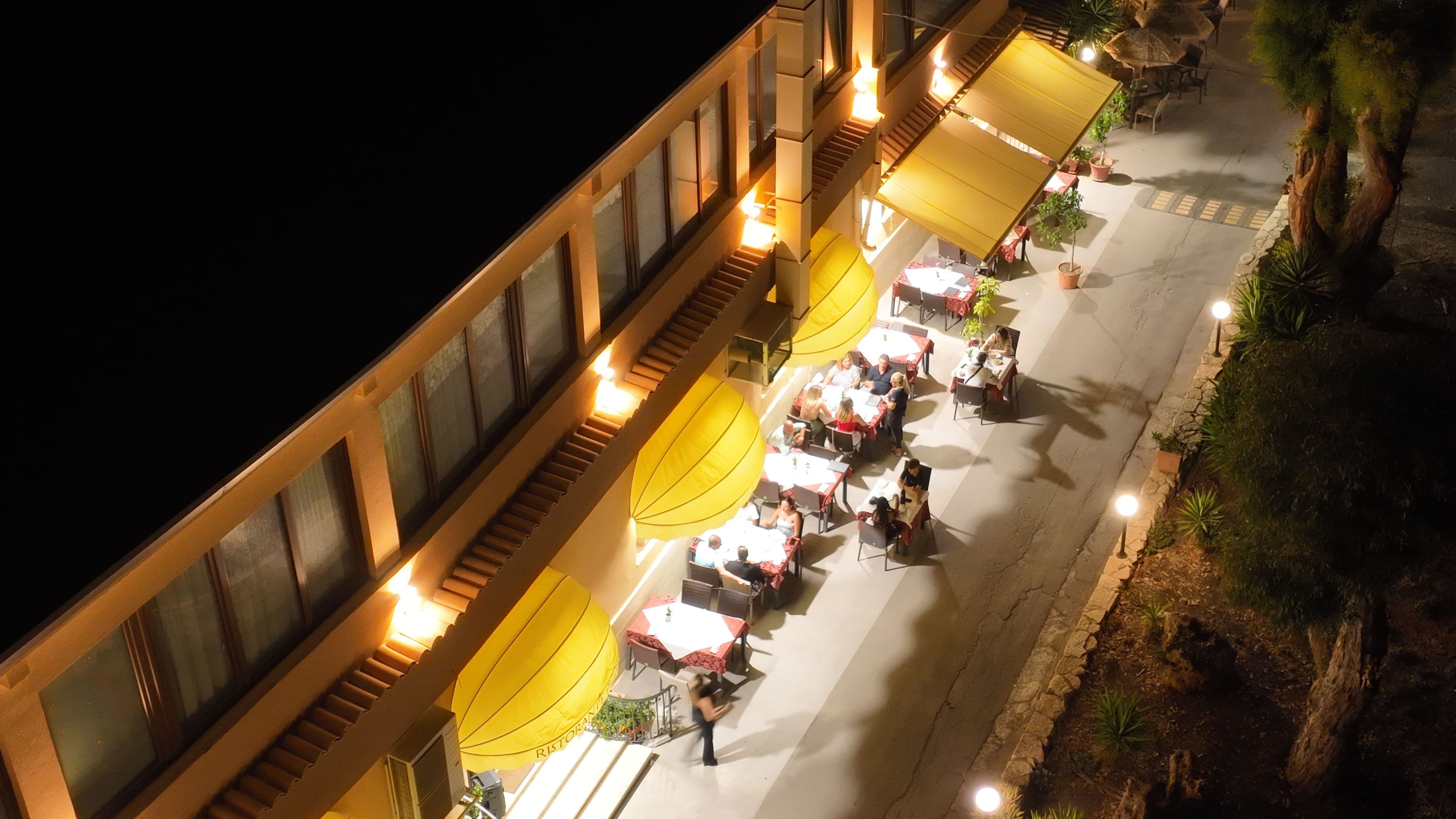 Ein Dachrestaurant mit Außenbestuhlung, einer Treppe und Blick auf die Stadtlandschaft.
