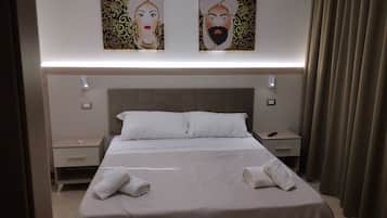 Una habitación de hotel con una cama grande, dos mesitas de noche, una lámpara de pared y una cortina.
