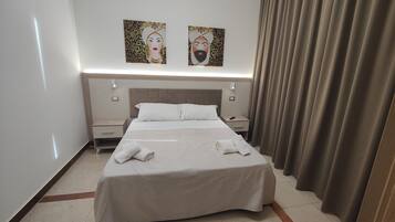 A hotel room with a bed, two nightstands, a headboard, and two wall-mounted artworks.