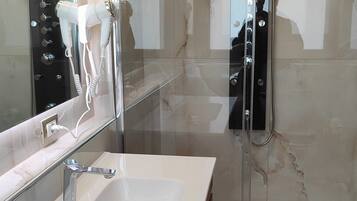 Ein modernes Badezimmer mit einer gläsernen Duschkabine, einem weißen Waschbecken und einem Spiegel.