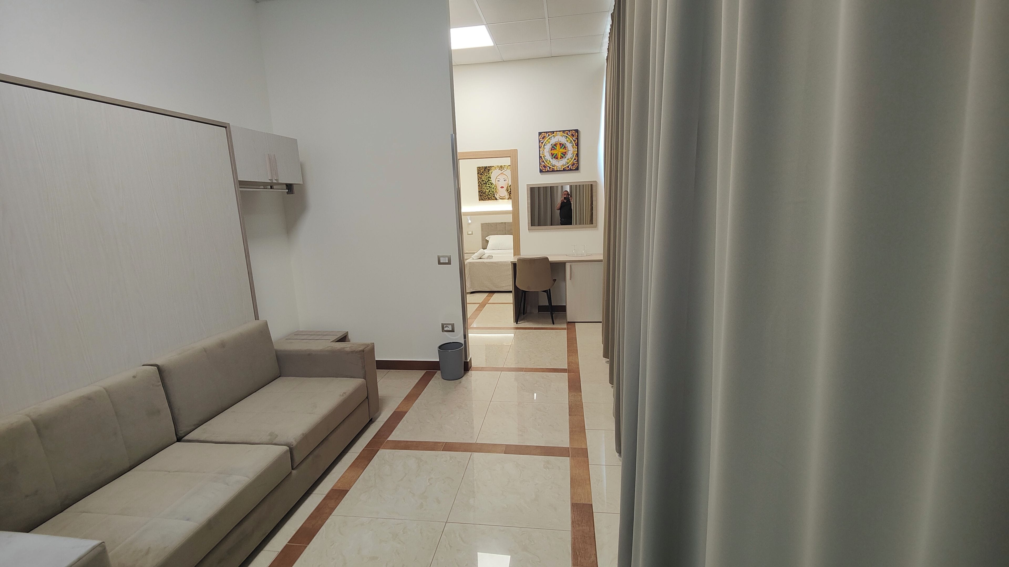 Une chambre d’hôtel avec un canapé, un bureau, un lit et une salle de bain que l’on aperçoit à l’arrière-plan.