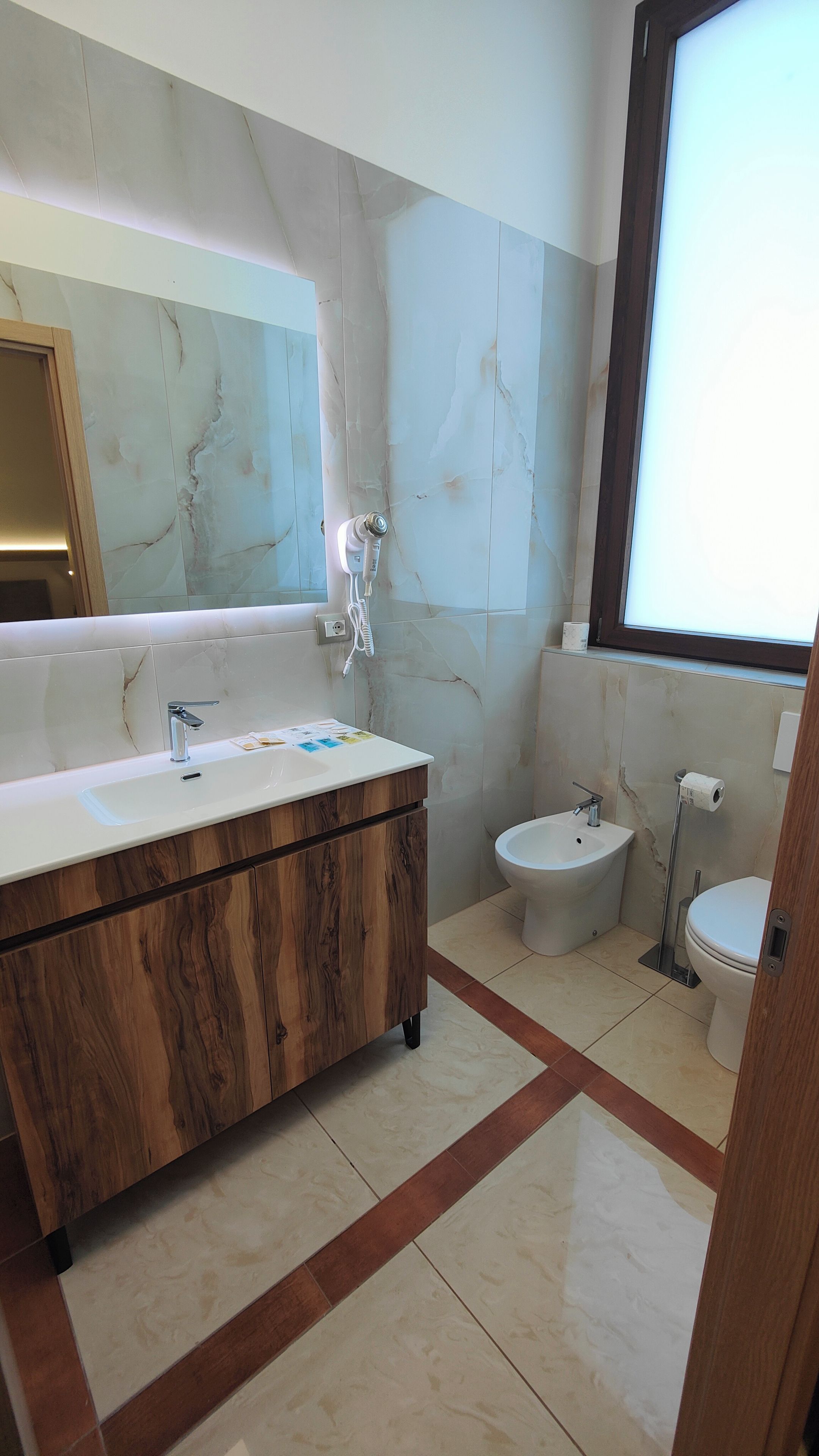 Een badkamer met een marmeren wastafel, toilet en bidet.