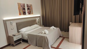 Habitación de hotel con cama, mesita de noche y escritorio con silla.