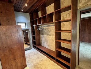 Ein begehbarer Kleiderschrank mit mehreren Holzböden und einer Kleiderstange.