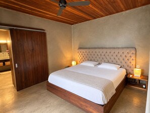 Ein Schlafzimmer mit einem großen Bett, einem Holzkopfbrett, zwei Nachttischlampen und einem Deckenventilator.