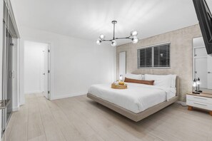A bedroom with a bed, bedside table, lamp, and a ceiling light fixture. - Heated Pool + Backyard Fun + Sleeps 12 + 15 Min to the Beach (Hollywood)