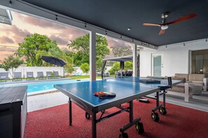 Ein Billardtisch mit Blick auf einen Swimmingpool und einen Außenbereich mit Sitzgelegenheiten.